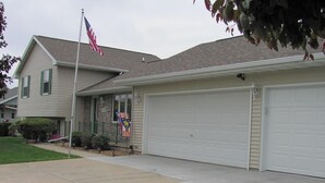 A two-story house with a garage, a flag, and a well-maintained lawn. - 3 Bedroom, 2 Bathroom Home - EAA Rental Only (Oshkosh)