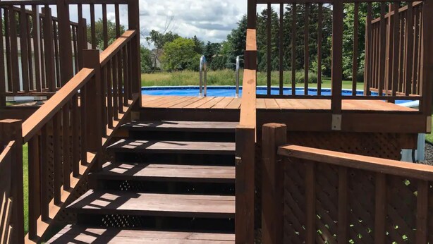 A wooden deck leading to a swimming pool with a metal ladder and a small waterfall feature. - 3 Bedroom, 2 Bathroom Home - EAA Rental Only (Oshkosh)