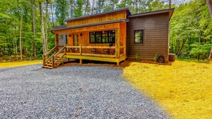 A cabin with a wooden deck, a covered porch, and a gravel driveway. - NEW Modern Cabin! 
2 King suites, hot tub, fire-pit and 2 fireplaces! (McCaysville)