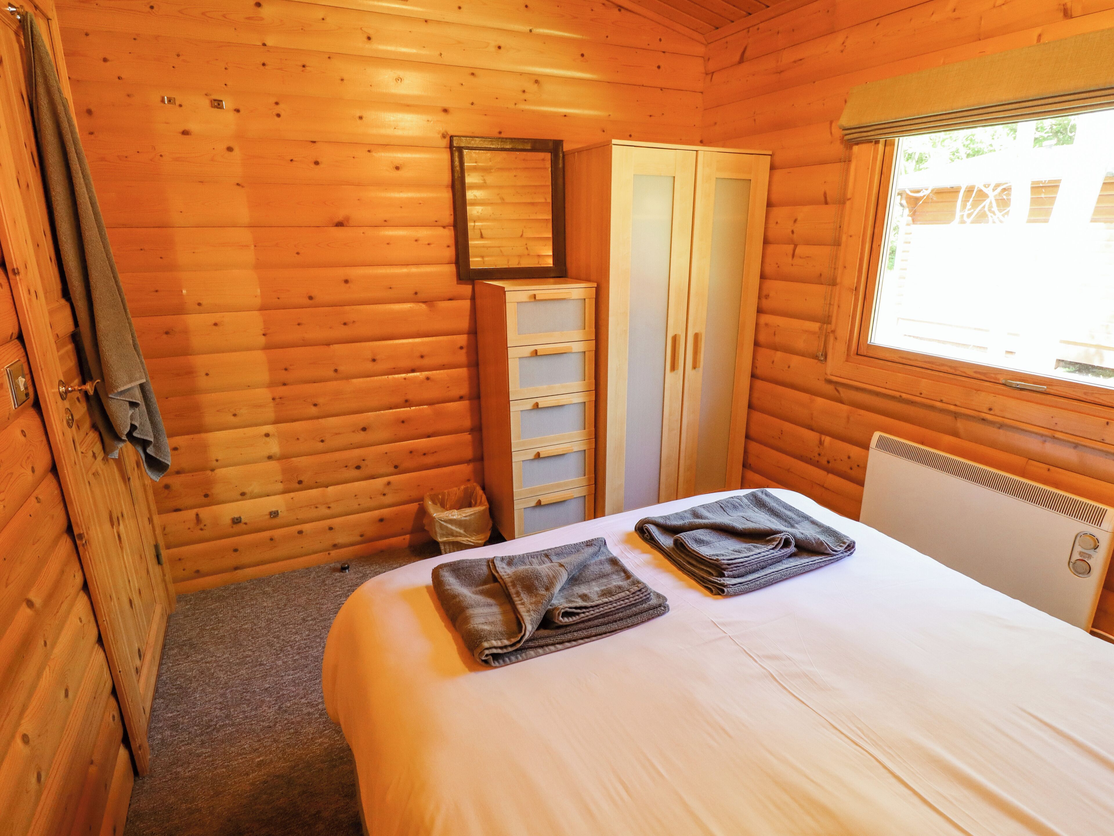 Een houten kamer met een bed, een kledingkast en een radiator.