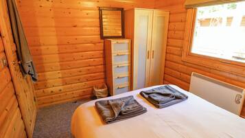 Een houten kamer met een bed, een kledingkast en een radiator.
