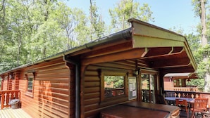Une cabane en bois dotée d’une terrasse, d’un bain à remous et d’un espace repas avec mobilier d’extérieur.