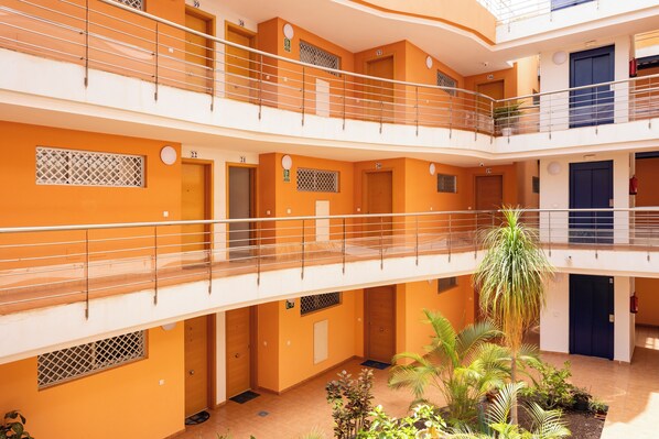 A multi-level atrium with balconies, doors numbered 22 to 39, and a central garden area with plants. - Stunning Beachfront Getaway, Your Perfect Retreat, Wifi, Garage, Sunset !!! (Guía de Isora)