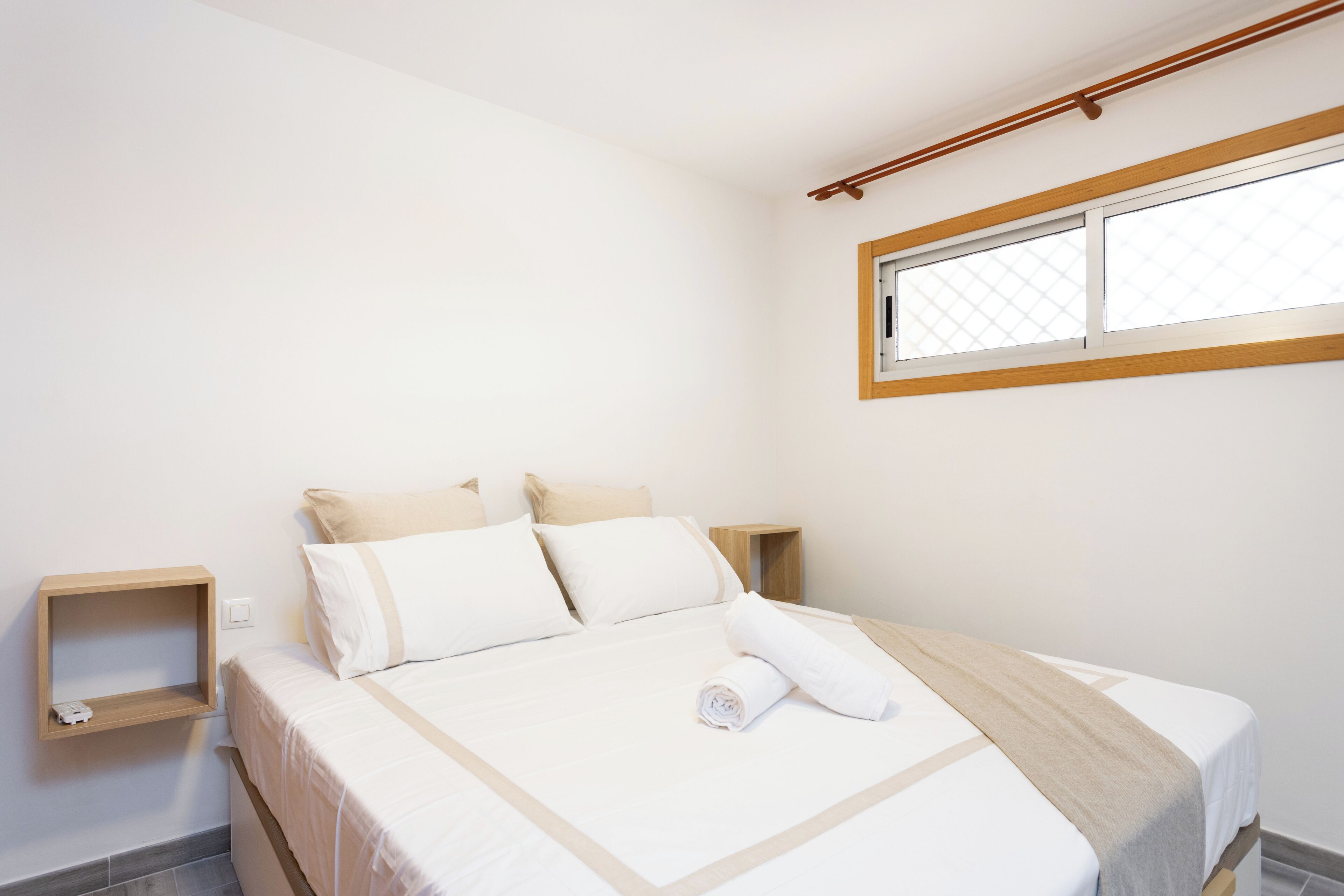 A bedroom with a bed, a window, and a nightstand.