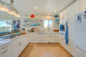 A modern kitchen with white cabinets, a stainless steel sink, and a built-in oven.