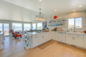 A spacious kitchen with white cabinets, a large island, and a view of the ocean. - Stunning Home in Coupeville w/ Deck + Beach Access (Coupeville)