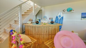 Ein Zimmer mit einer Rezeption aus Bambus, einer Treppe und einer Strand-Dekoration, darunter ein Surfbrett und Muscheln.