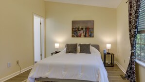 A bedroom with a large bed, two bedside tables with lamps, a painting on the wall, and a window with curtains. - 4 Mi to Dtwn: Pet-Friendly Abode in Tallahassee! (Tallahassee)