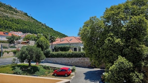 A residential area with houses, a red car parked in the driveway, and a clear blue sky.