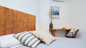 A bedroom with a wooden headboard, a bed with striped pillows, a bedside table with a vase, and a chair.