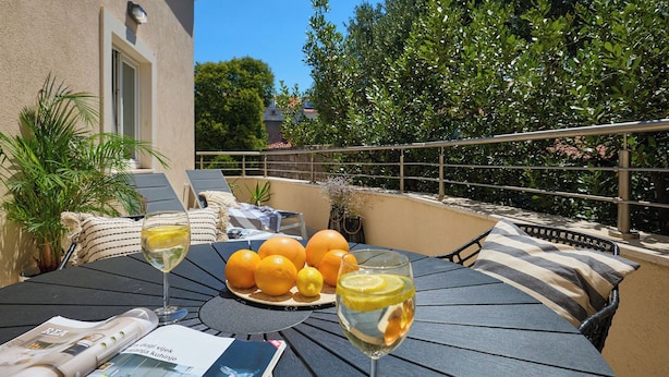 A table with a glass of white wine, oranges, and a newspaper.