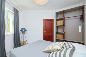 A bedroom with a bed, a wardrobe, a floor lamp, and a door. - Hedera Estate, Hedera A41 (Dubrovnik)