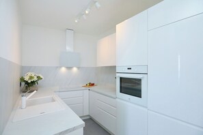 Una cocina moderna con armarios blancos, horno empotrado y encimera con un jarrón de flores.