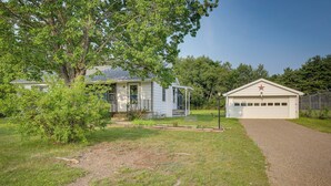 Une maison avec un garage, une allée et un grand arbre dans le jardin.