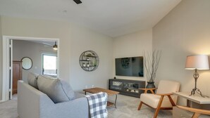 A living room with a grey sofa, a coffee table, a TV, and a lamp.