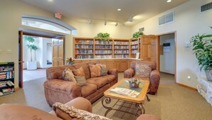 A spacious living room with a brown leather sofa set, a coffee table, and a bookshelf filled with books.