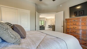 A bedroom with a bed, a dresser, and a ceiling fan.