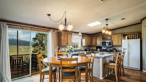 Una cocina con armarios de madera, una mesa de comedor con sillas, una isla integrada y un amplio ventanal corredero que da a un balcón.