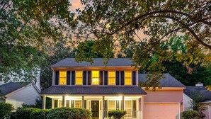 A two-story house with a covered front porch, a garage, and a well-maintained lawn. - Country Oasis w/ Game Rm, Mins from DWTN & Airport (North Charleston)