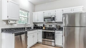 A modern kitchen with white cabinets, stainless steel appliances, and a black countertop. - Country Oasis w/ Game Rm, Mins from DWTN & Airport (North Charleston)