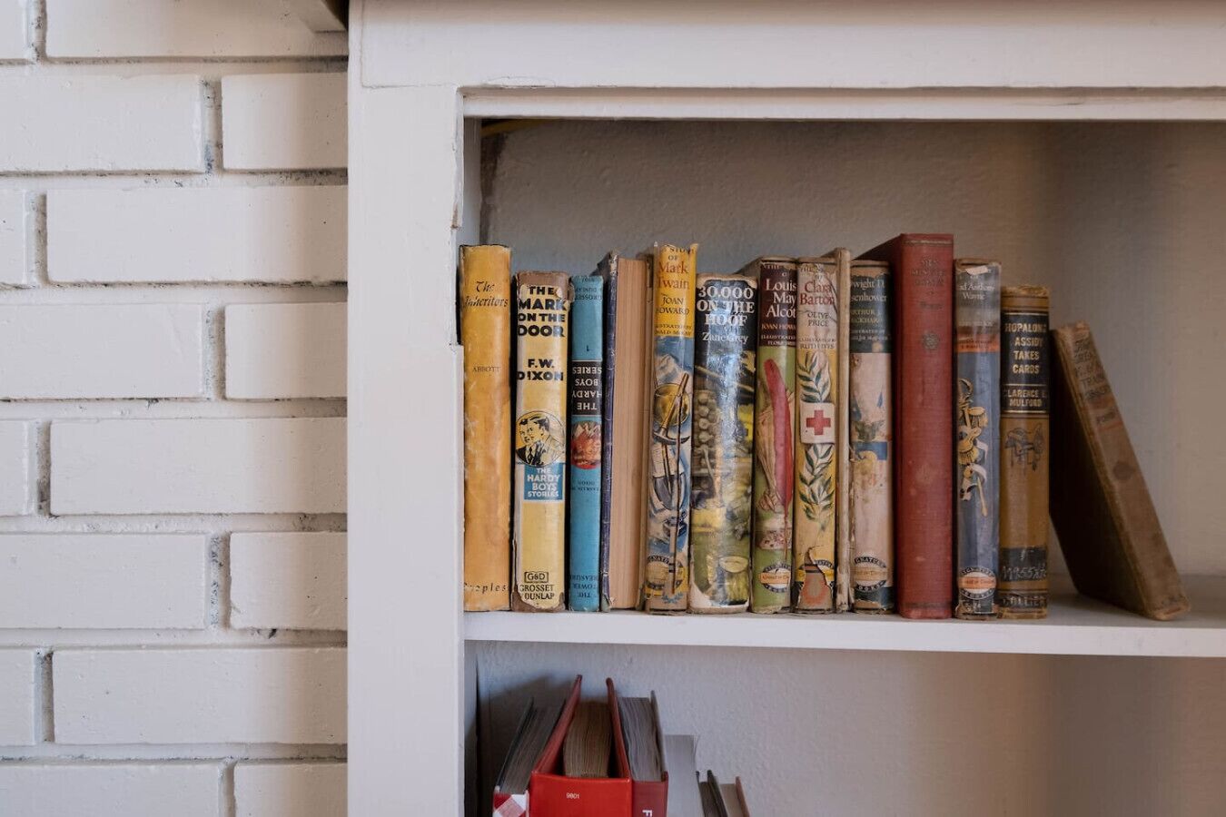 Une bibliothèque remplie de divers ouvrages, dont des titres comme « The Mark on the Door » et « 30 000 Feet Up ».
