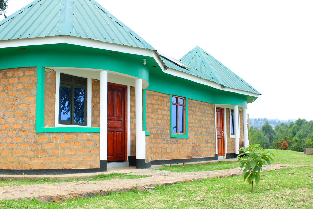 A two-story house with a brick exterior, green trim, and a metal roof.