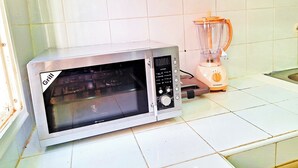 A kitchen with a microwave and a blender on a tiled floor. - Calm apartment, close to the beach + Chocolat gift
 (Agadir)