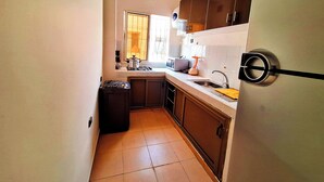 A compact kitchen with a stove, sink, and cabinets. - Calm apartment, close to the beach + Chocolat gift
 (Agadir)