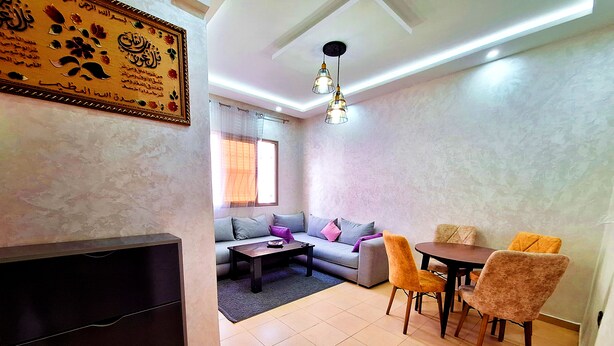 A living room with a sofa, coffee table, and dining area with chairs. - Calm apartment, close to the beach + Chocolat gift
 (Agadir)