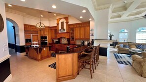 A spacious kitchen with wooden cabinetry, a central island, and a dining area with a sofa and coffee table.