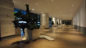 A modern hotel corridor with a long, open layout, featuring a central walkway flanked by large planters and columns. - The Elements at Jalan Ampang (Kuala Lumpur)