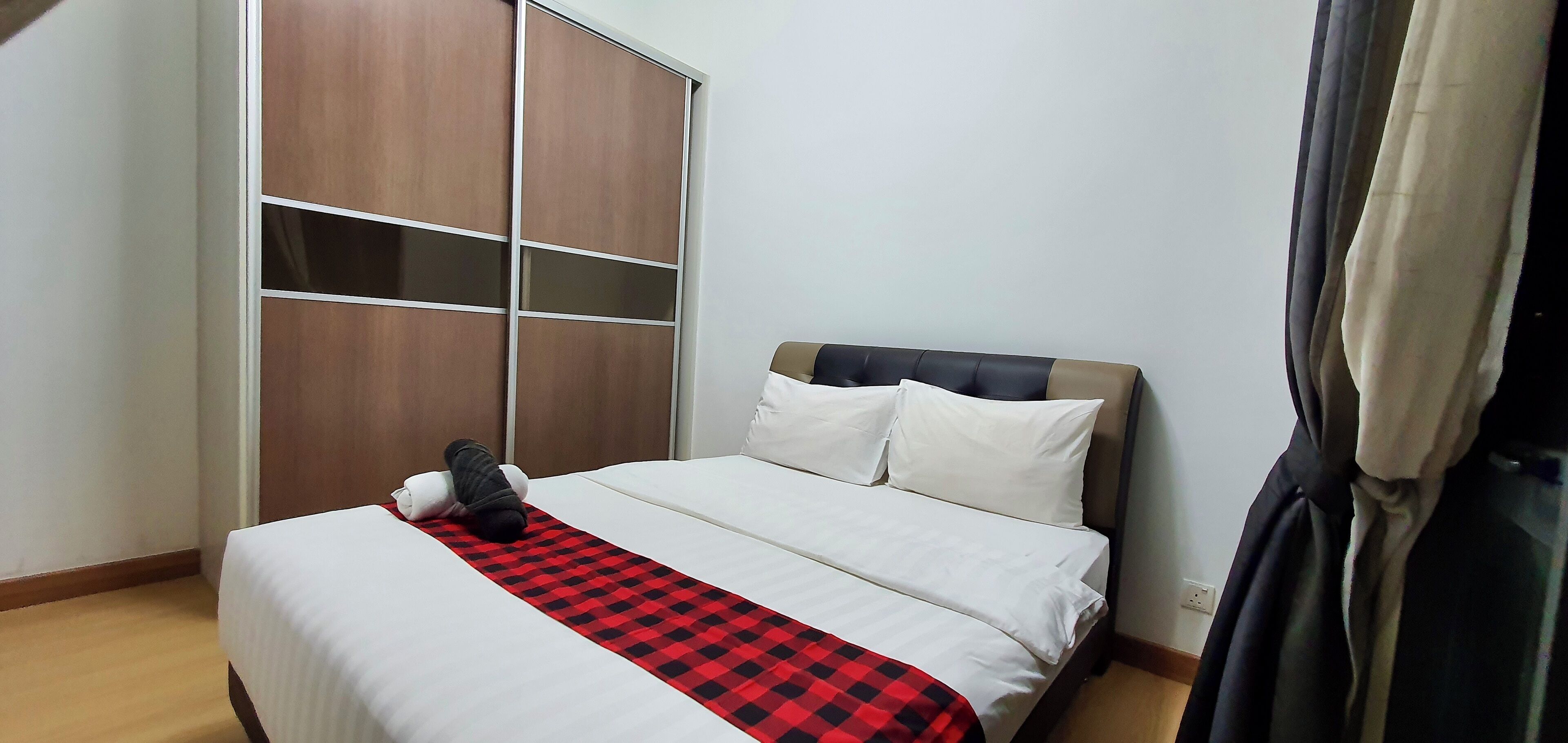Un dormitorio con cama, armario y ventana con cortinas.