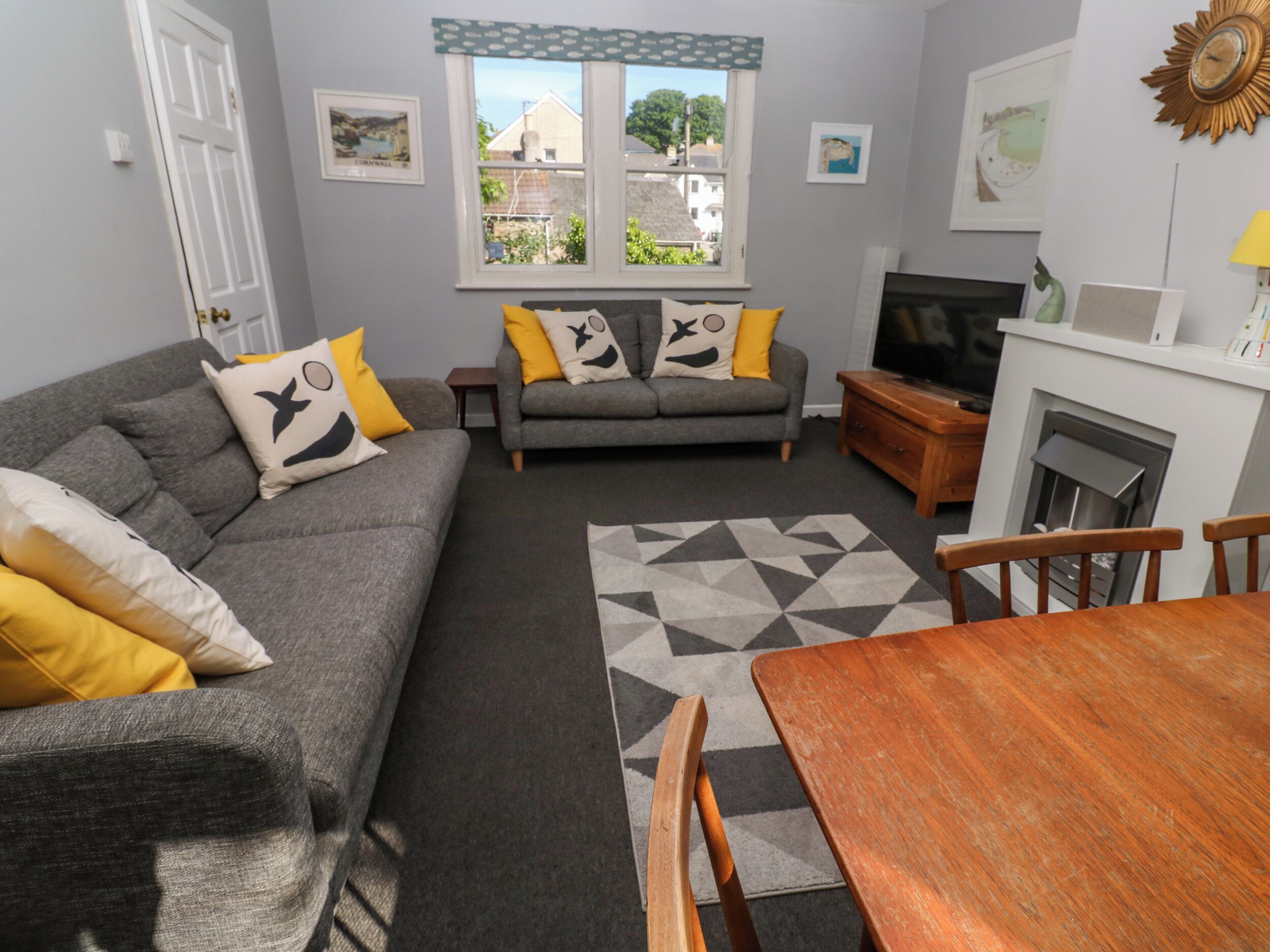 A living room with a grey sofa, yellow cushions, a TV, and a fireplace.