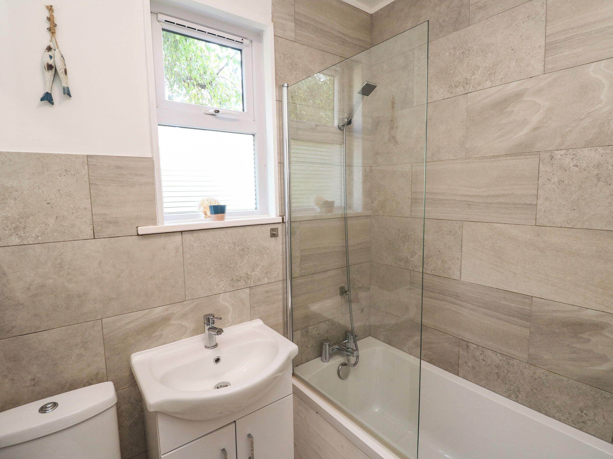A bathroom with a glass-enclosed shower, a sink, and a toilet.