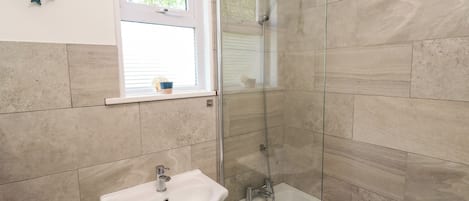 A bathroom with a glass-enclosed shower, a sink, and a toilet.