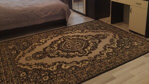 Ein Schlafzimmer mit Bett, Kleiderschrank, Schreibtisch mit Spiegel und einem Teppich mit Muster.