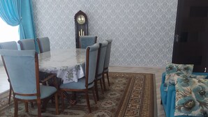 Ein Essbereich mit Tisch und Stühlen, einem gemusterten Teppich und einer Couch mit Blumenkissen.
