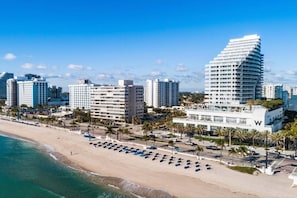 Um hotel à beira-mar com vista para a praia, vários andares e um design curvo característico.
