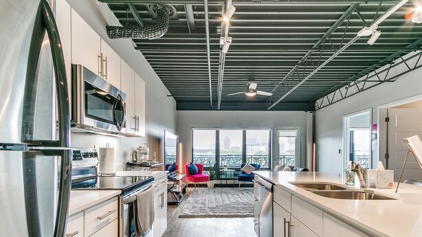 A modern kitchen with stainless steel appliances, a dining area with a view, and a large window. - The Cartier Lux DT Apt w/Skyline View (Des Moines)