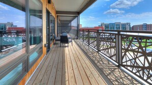 A wooden deck with glass doors leading to a balcony, offering a view of the cityscape. - The Cartier Lux DT Apt w/Skyline View (Des Moines)