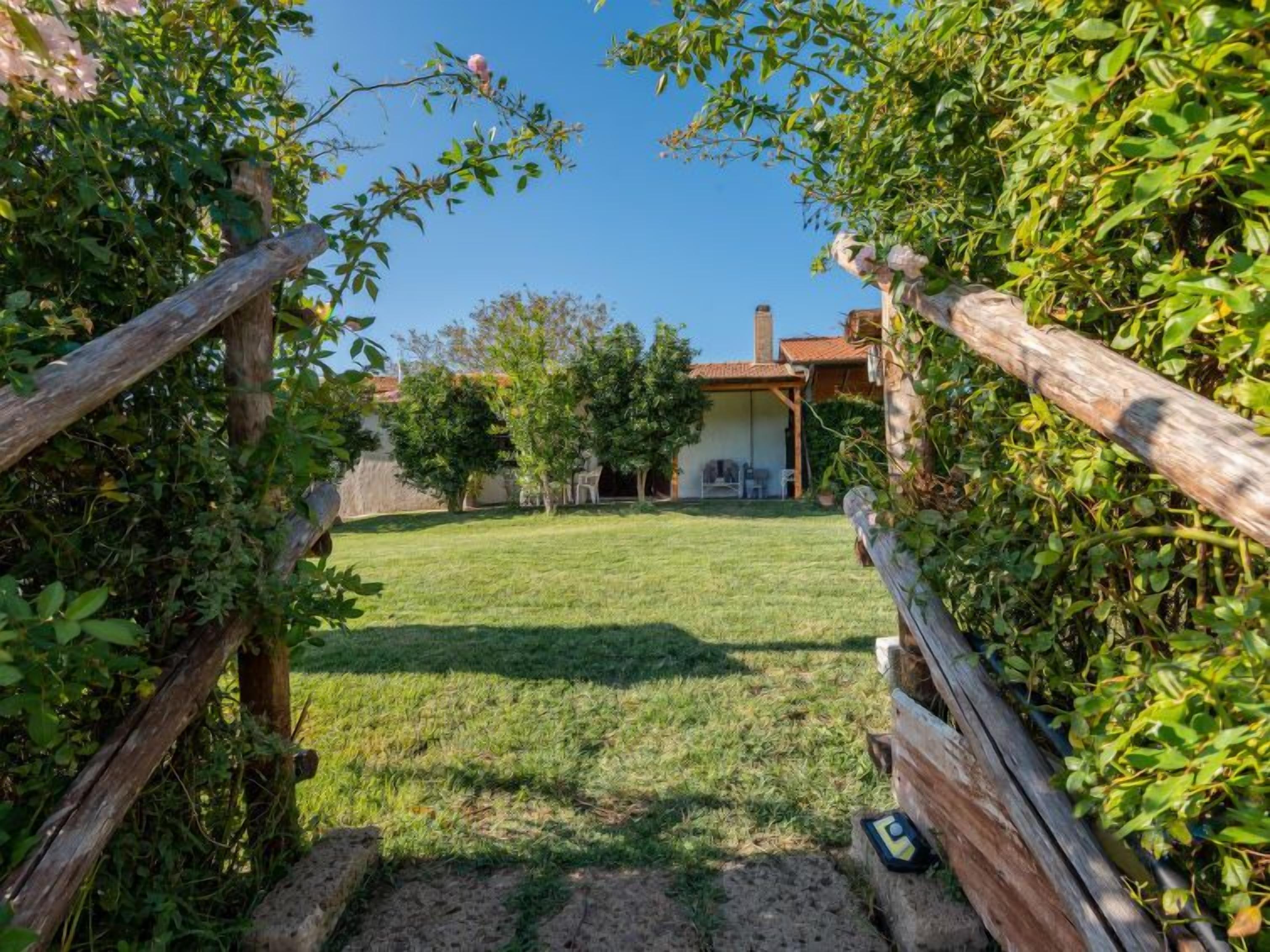 Un chemin menant à une maison dotée d’un jardin, d’une terrasse et d’une cheminée bien visible.
