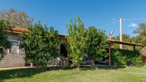 Une maison avec une façade en pierre, une pergola en bois et une pelouse bien entretenue.