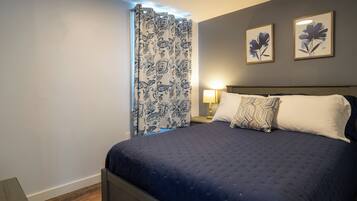 A bedroom with a bed, a nightstand, a lamp, and two framed floral paintings on the wall.