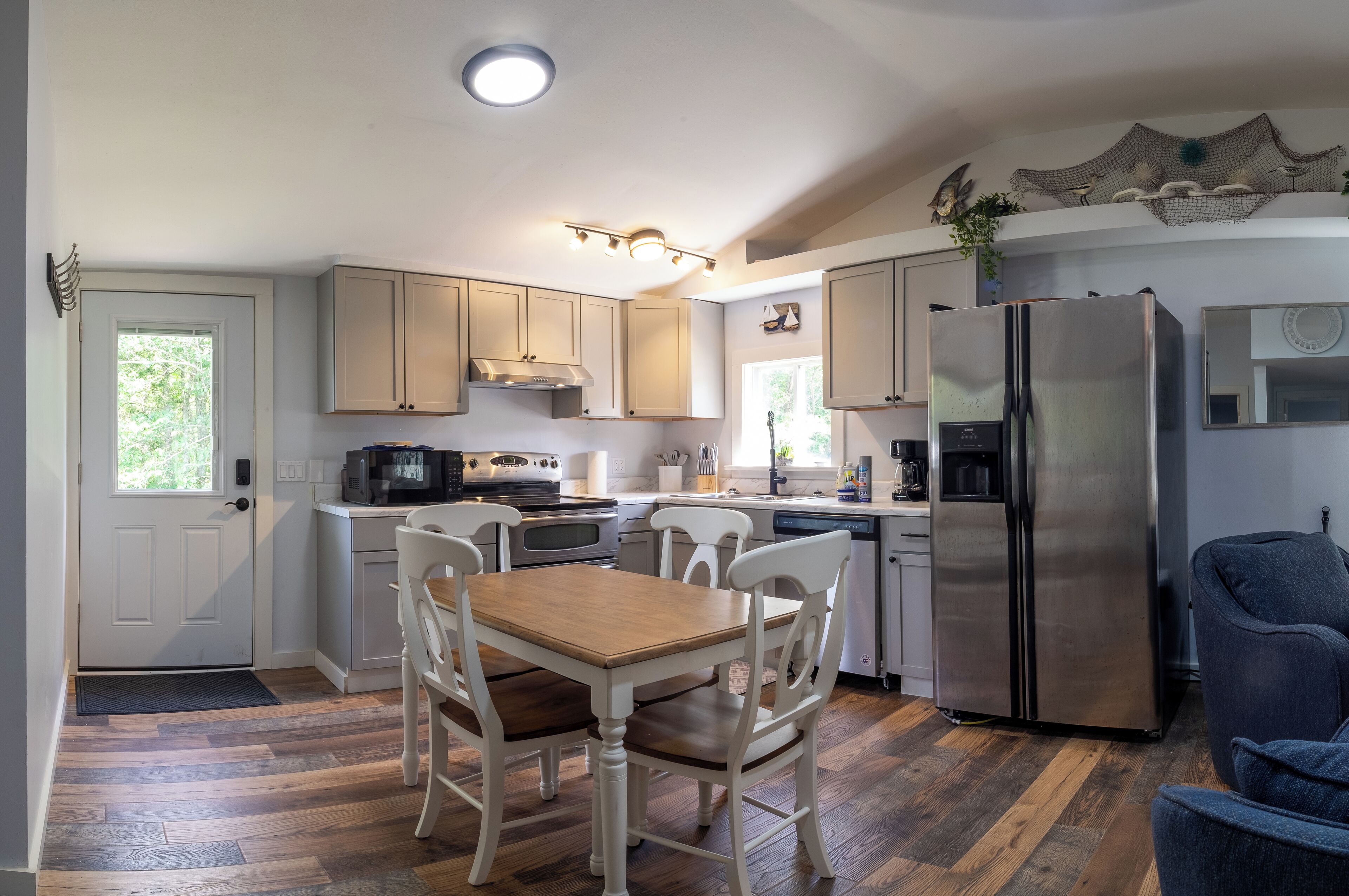 A modern kitchen with wooden cabinets, a stainless steel refrigerator, and a dining table with chairs.