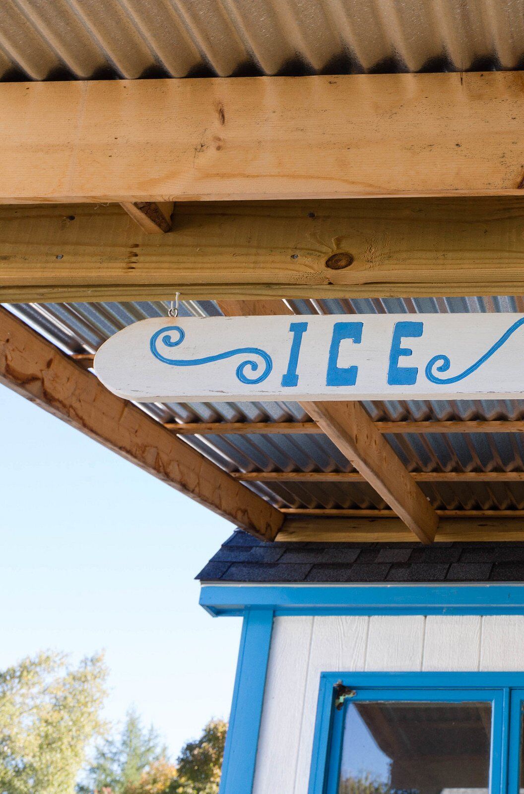 A wooden structure with a corrugated metal roof and a sign that reads "ICE".