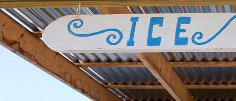 A wooden structure with a corrugated metal roof and a sign that reads "ICE".