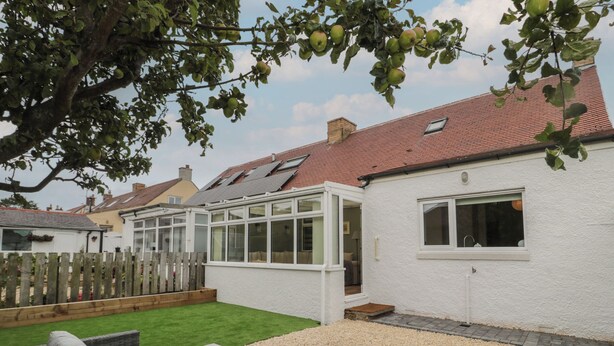 A house with a conservatory, a fenced garden, and outdoor seating. - Gudhjem (Seahouses)