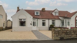 A two-story house with a pitched roof, a small attached garage, and a gravel driveway. - Gudhjem (Seahouses)