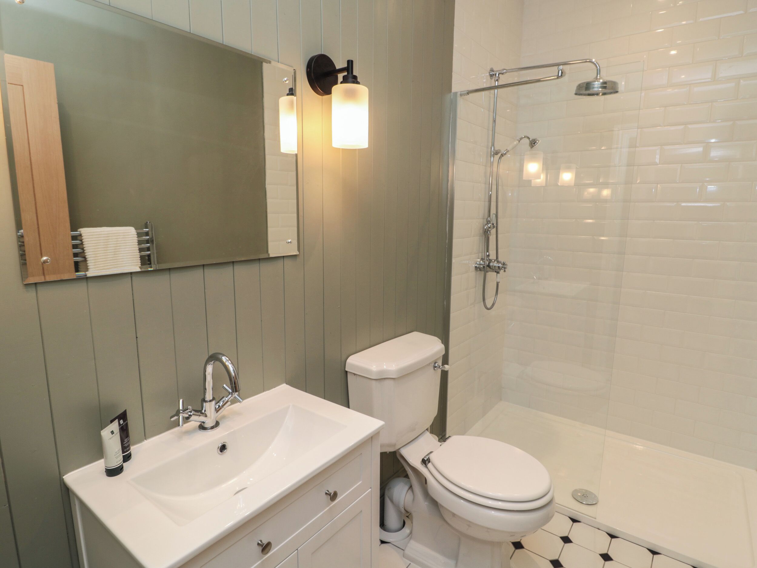 A modern bathroom with a white sink, toilet, and shower.