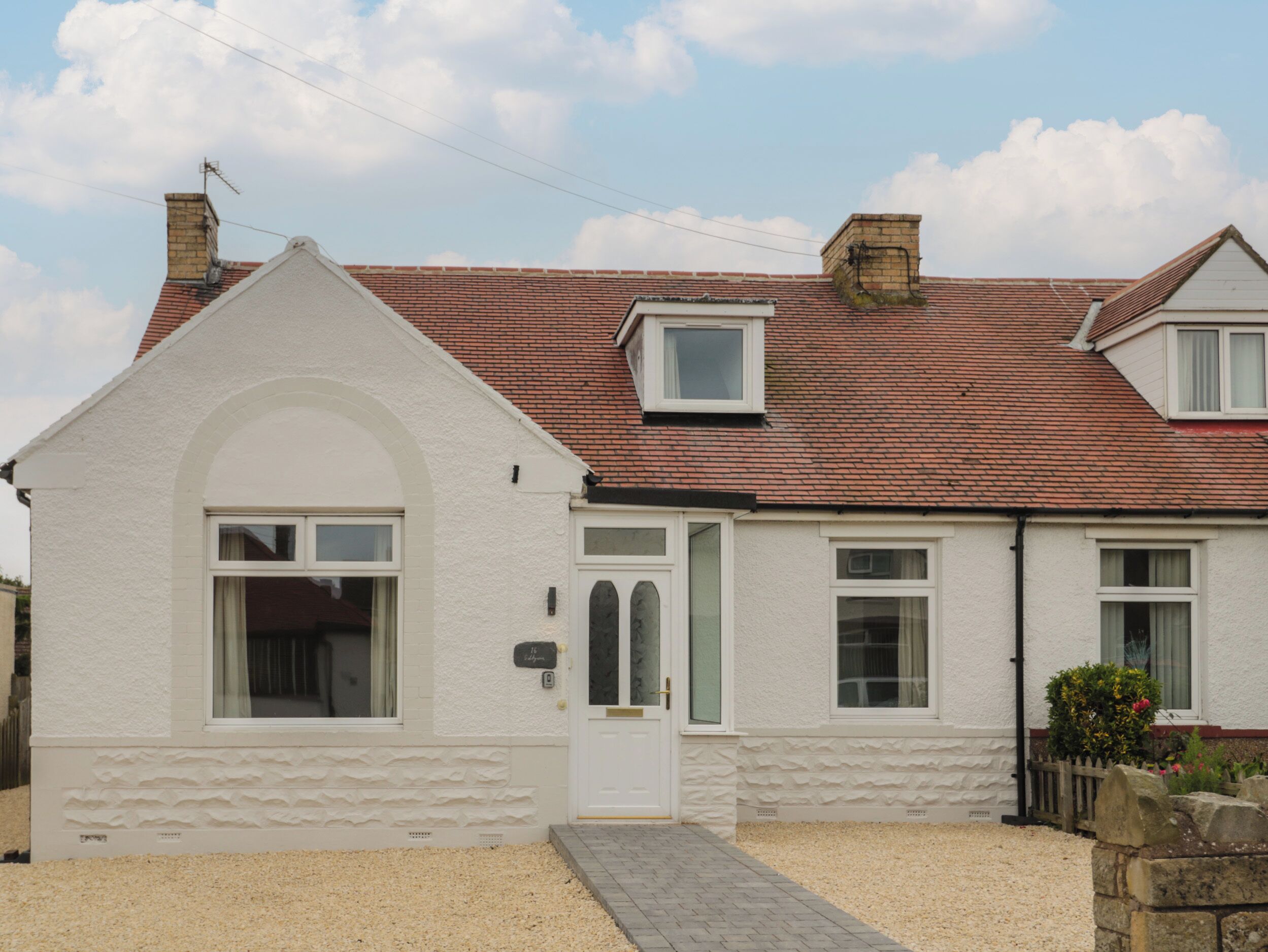 A single-story house with a white exterior, a red-tiled roof, and a small attached garage.
